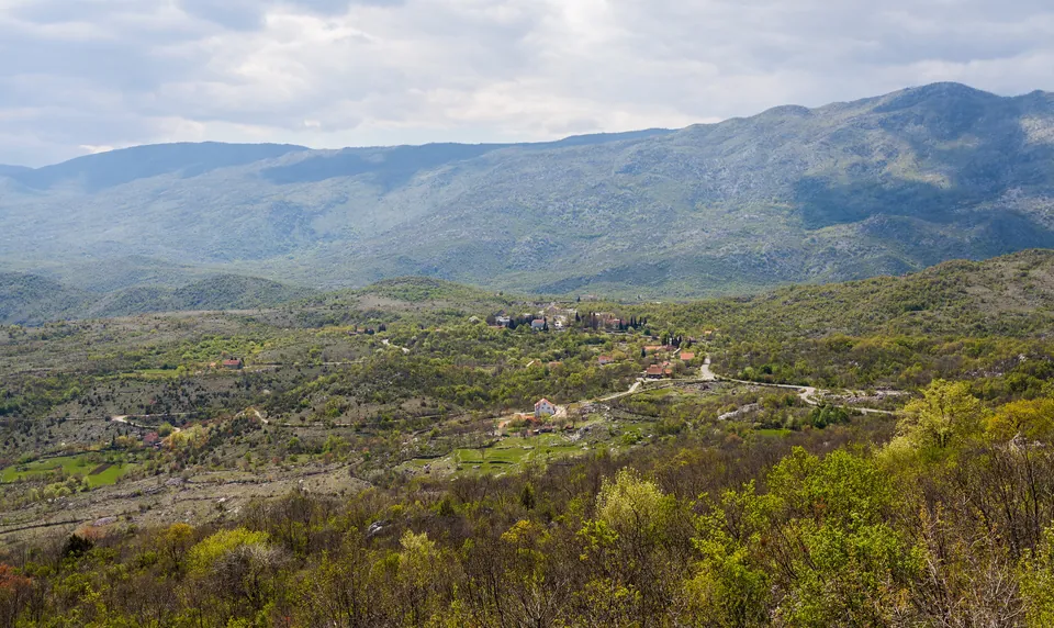 View from a hillside near Ostrog Monastery over a small village and green valley.
