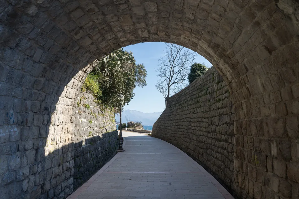 Stone archway of the seaside promenade in Herceg Novi opening toward the bay