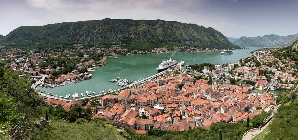 Aerial panorama of Kotor's old town, bay and surrounding mountains with a cruise ship docked