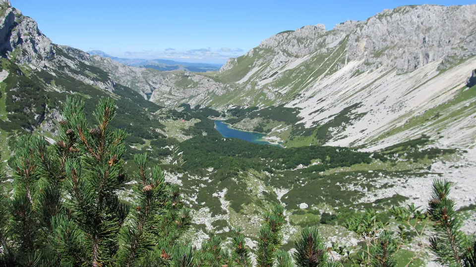 Turquoise mountain lake seen from a rocky trail winding through Durmitor's stony peaks