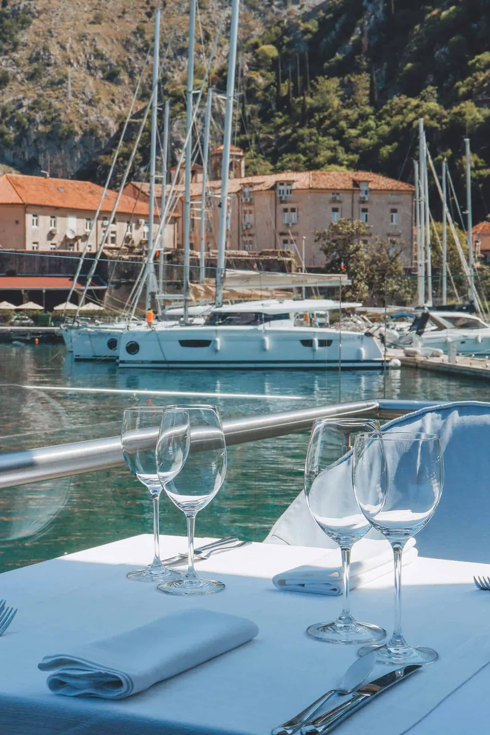 Glasses and blue napkins on a terrace table facing the marina
