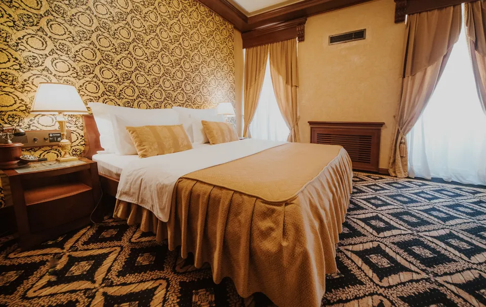 Guest room with patterned wallpaper and a gold bedspread