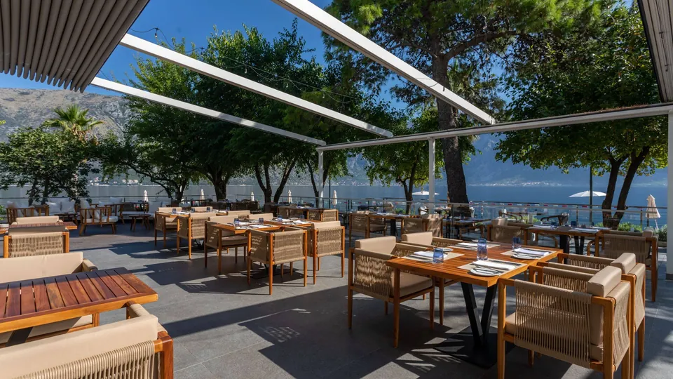 Shaded restaurant terrace with tables facing the bay