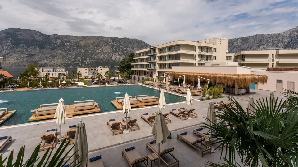 Outdoor pool with parasols and the resort buildings behind