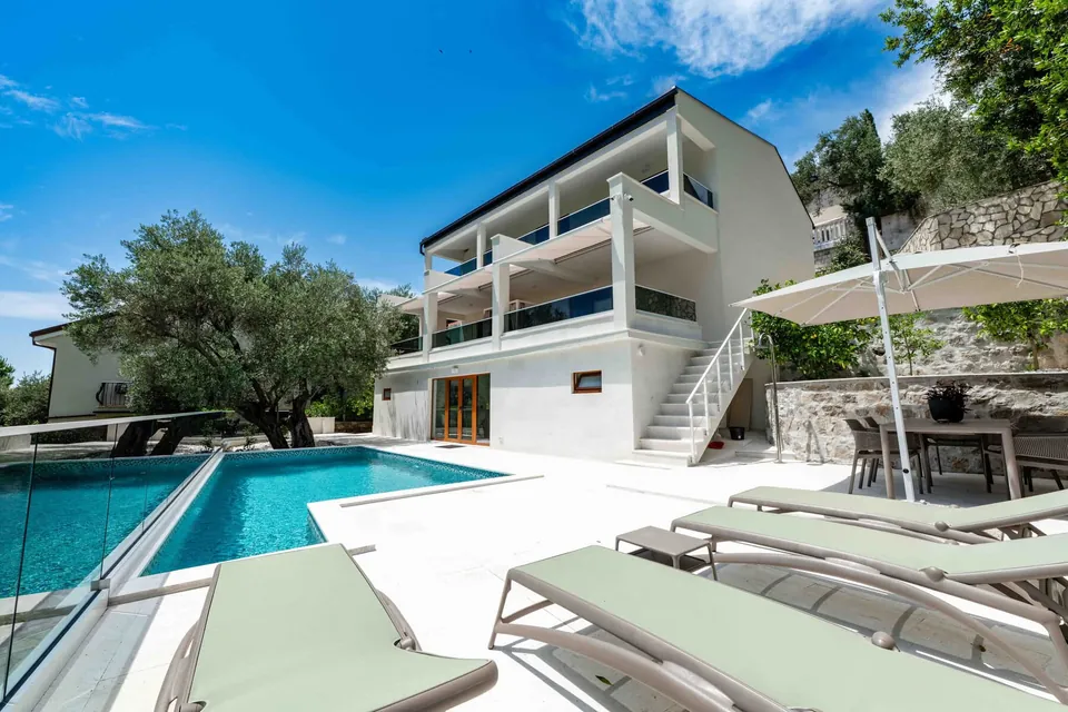 Pool terrace with loungers beside a white villa