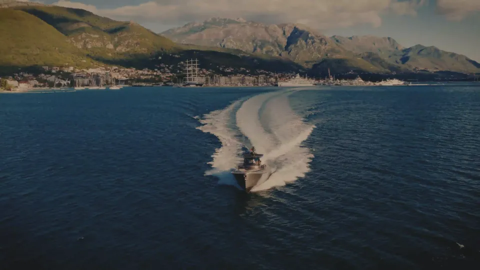 A boat crossing the bay at dusk below the mountains