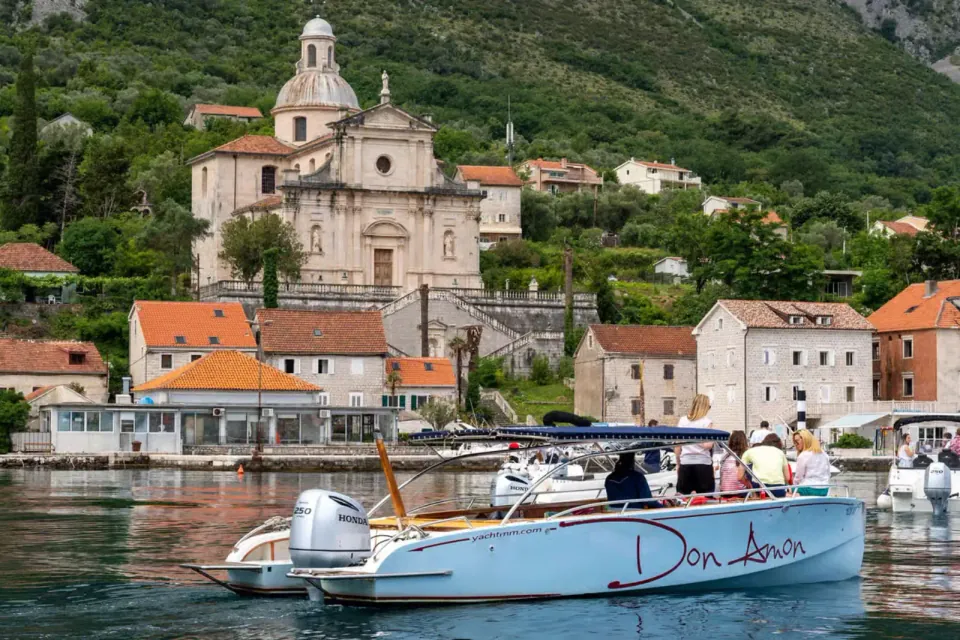 Boat moored below a church on the shore of the bay
