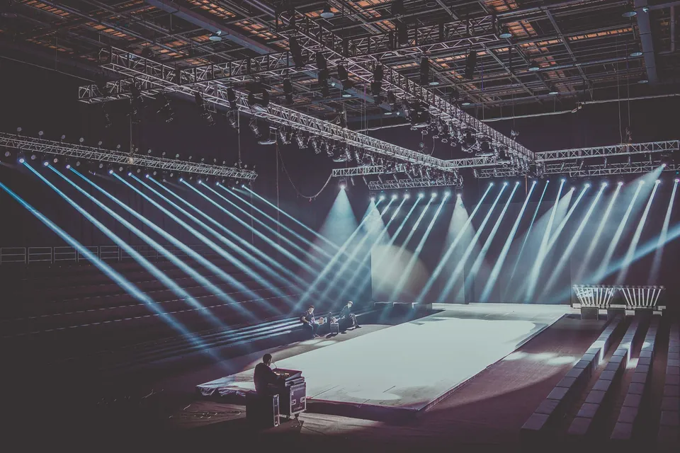 Lighting trusses and moving head beams over an empty runway stage