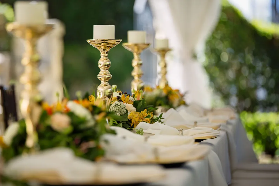 Banquet table with gold candlesticks, flowers and folded napkins