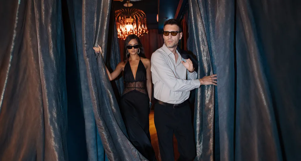 Guests stepping through velvet curtains into the evening